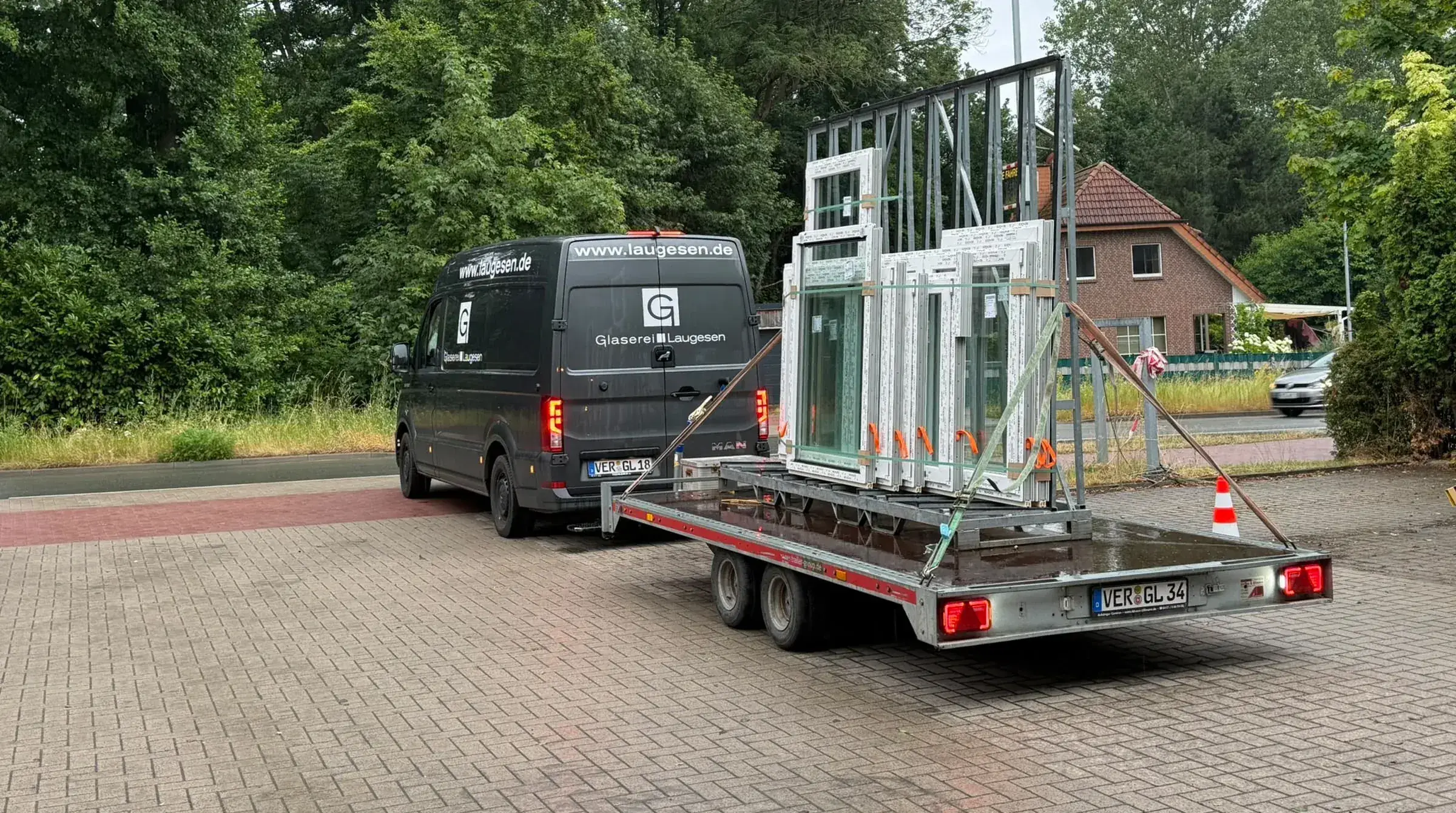 Transporter und Anhänger der Glaserei Laugesen mit Fenstern auf dem Weg zur Baustelle