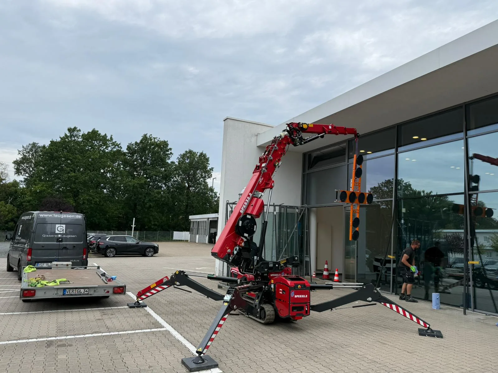 Jekko-Minikran der Glaserei Laugesen setzt mit Saugtraverse eine Schaufensterscheibe an einem Autohaus ein